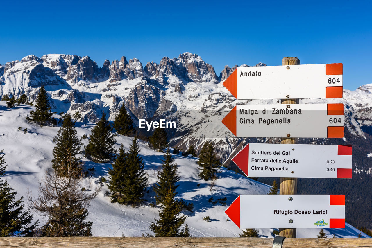 INFORMATION SIGN ON SNOW AGAINST MOUNTAIN