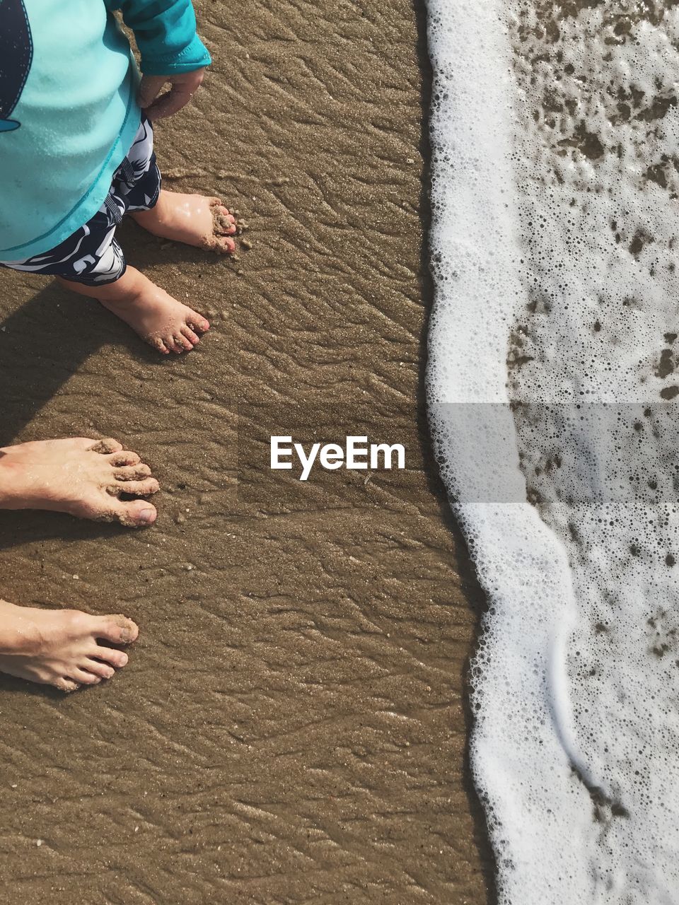 Low section of family standing at beach