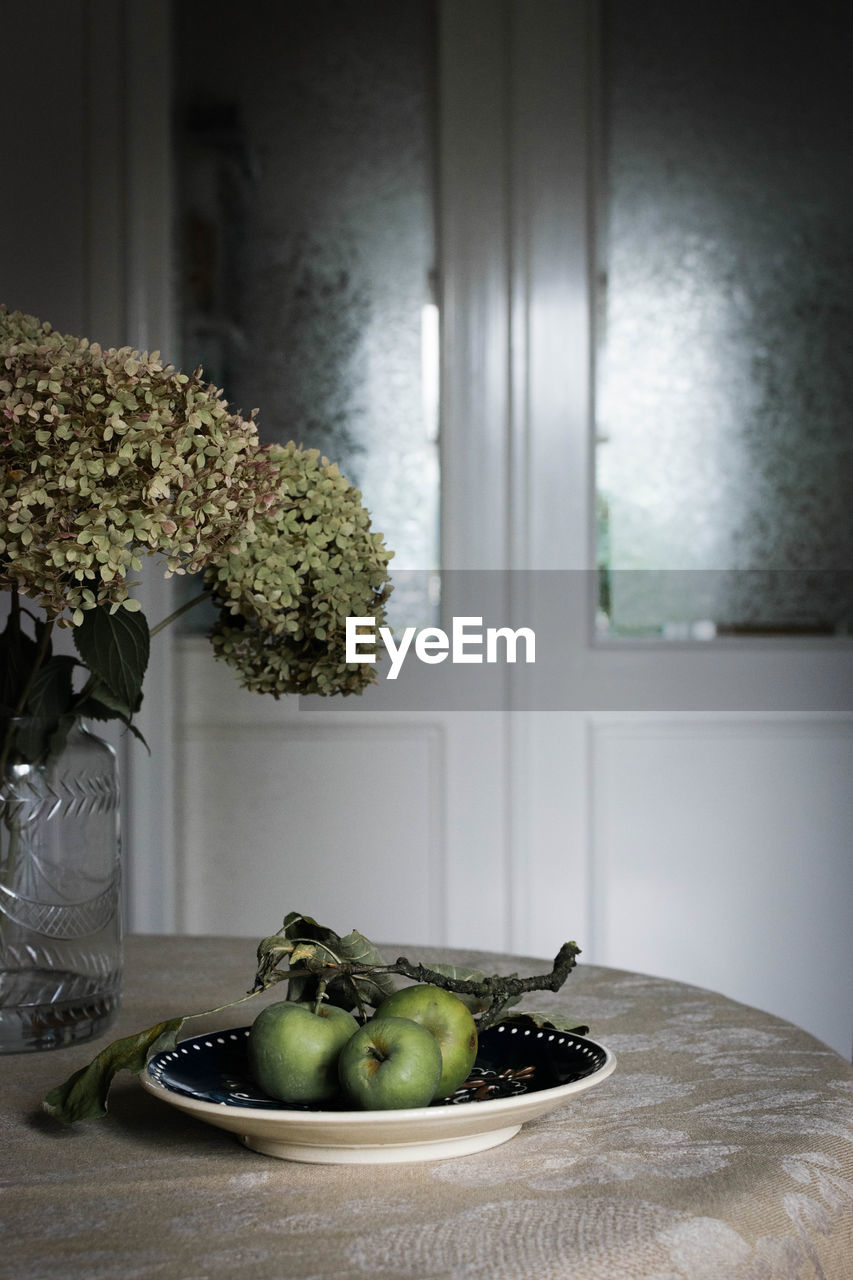 Close-up of vase and fruits on table at home