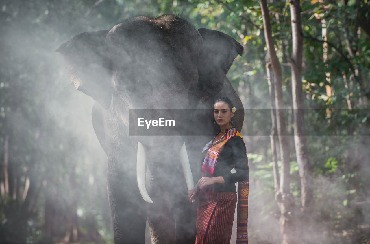 Portrait of smiling woman standing with elephant in temple