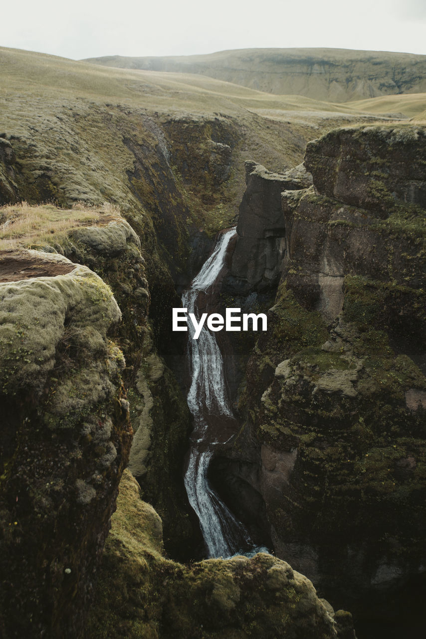 SCENIC VIEW OF WATERFALL ON ROCK FORMATION