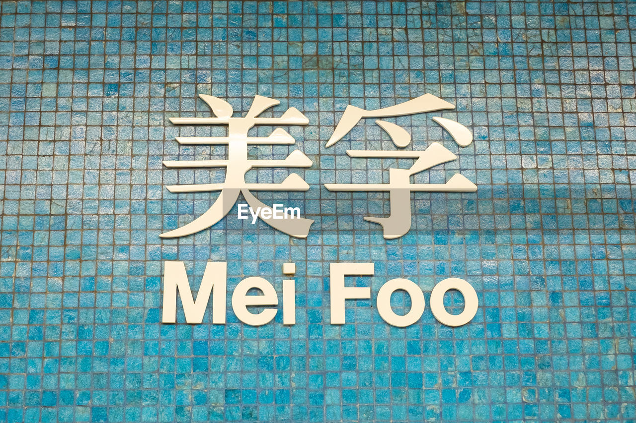 CLOSE-UP OF TEXT ON BLUE WALL BY SWIMMING POOL