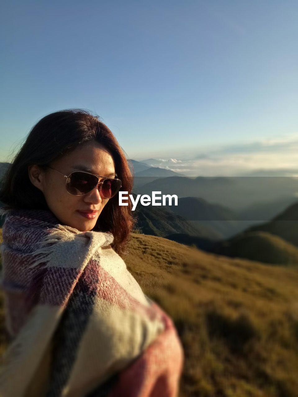 Side view portrait of woman wearing sunglasses on mountain against clear sky