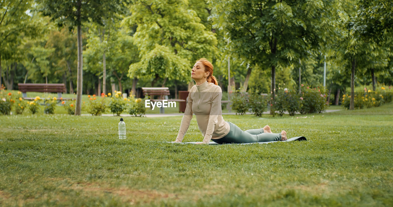 Yogi outdoors, stretching back in the park. raining and stretching muscles, tendons, bones