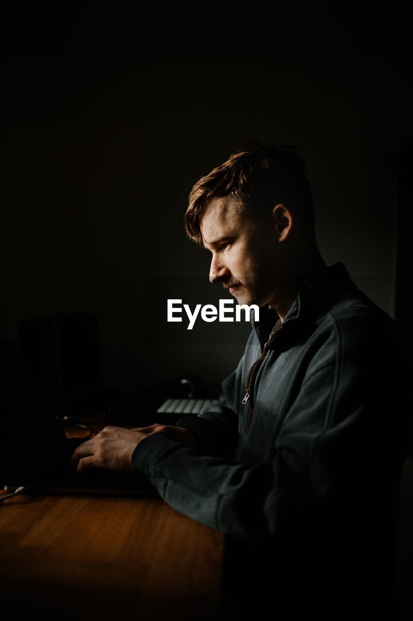 Young man using laptop in darkroom