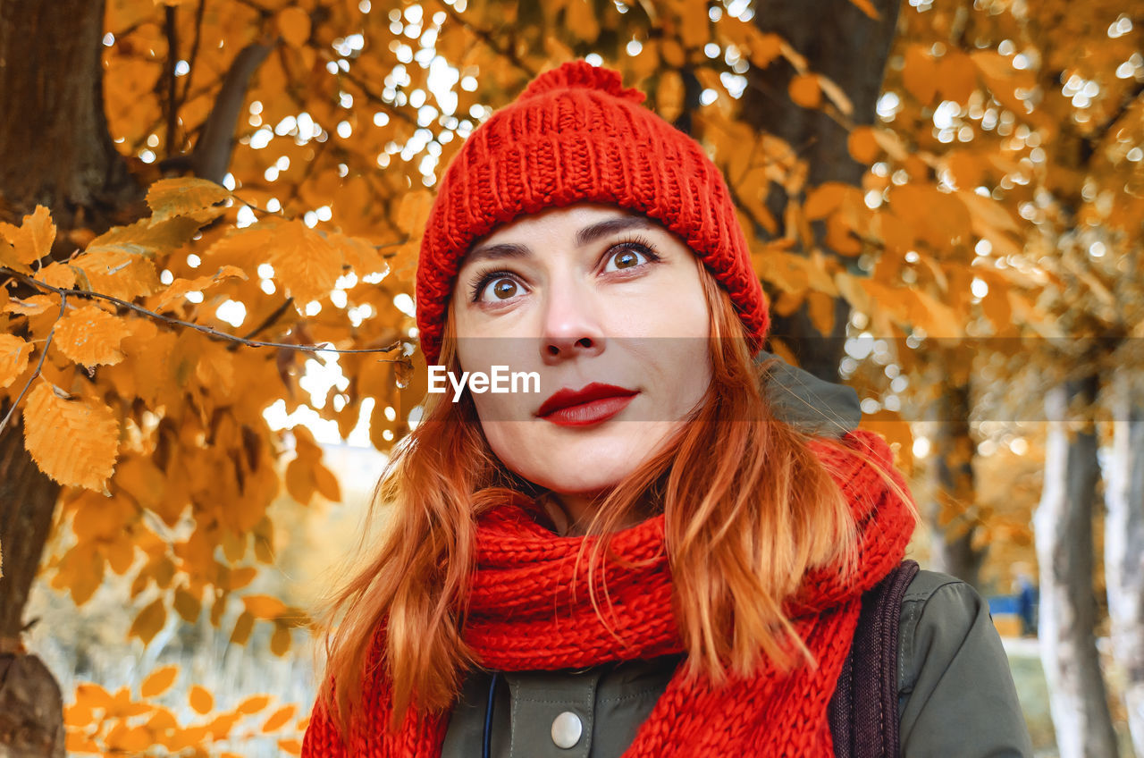 Dreamy woman with red hair and black eyes enjoying nature in autumn forest. yellow leaves.