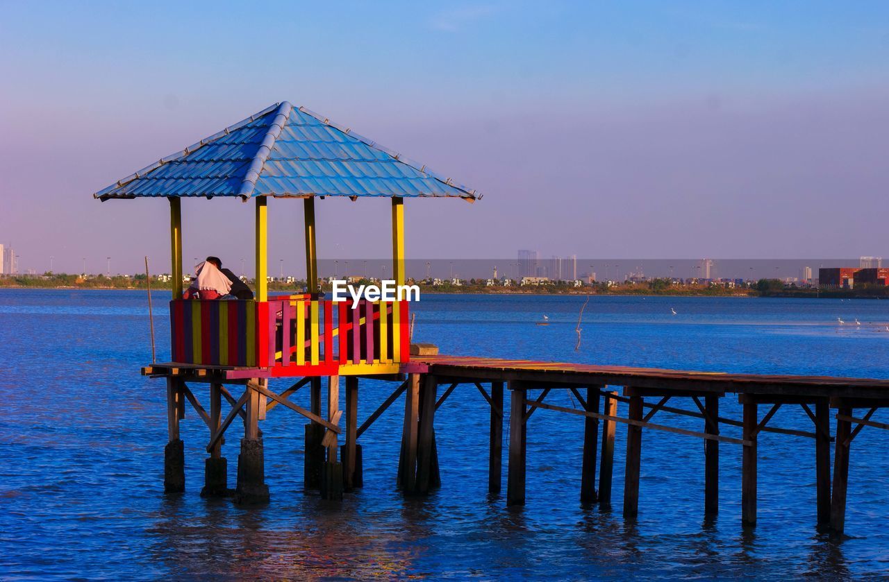 Gazebo by sea against blue sky