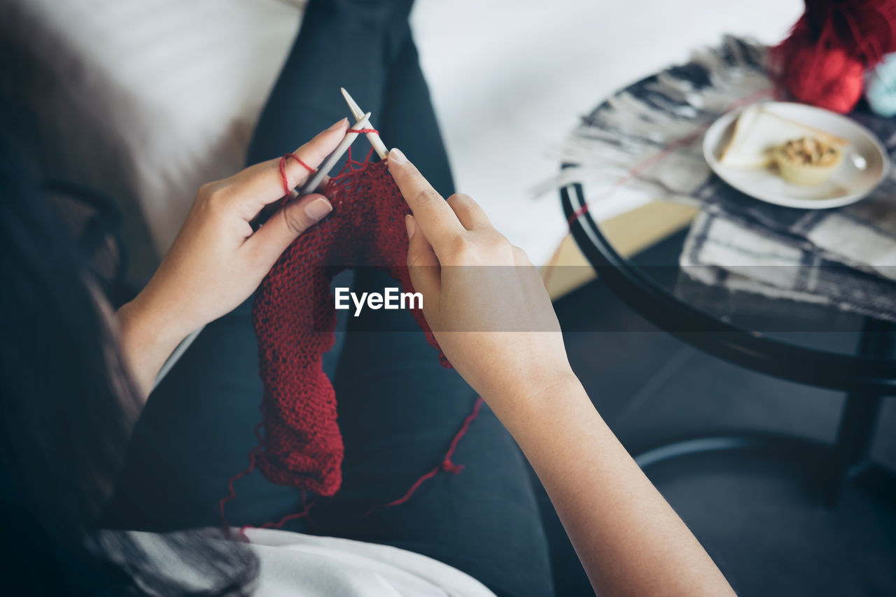 Midsection of woman knitting wool at home