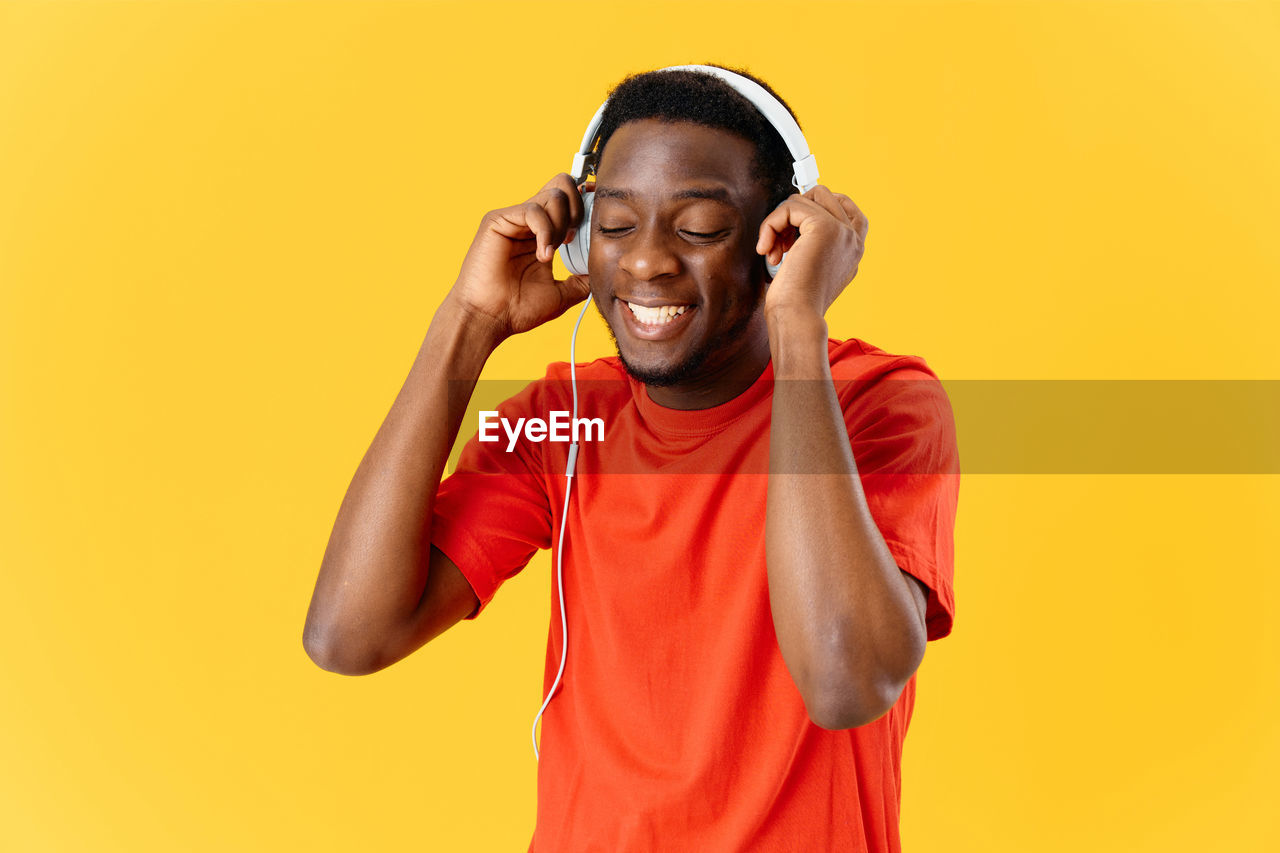 Smiling young man standing against yellow background