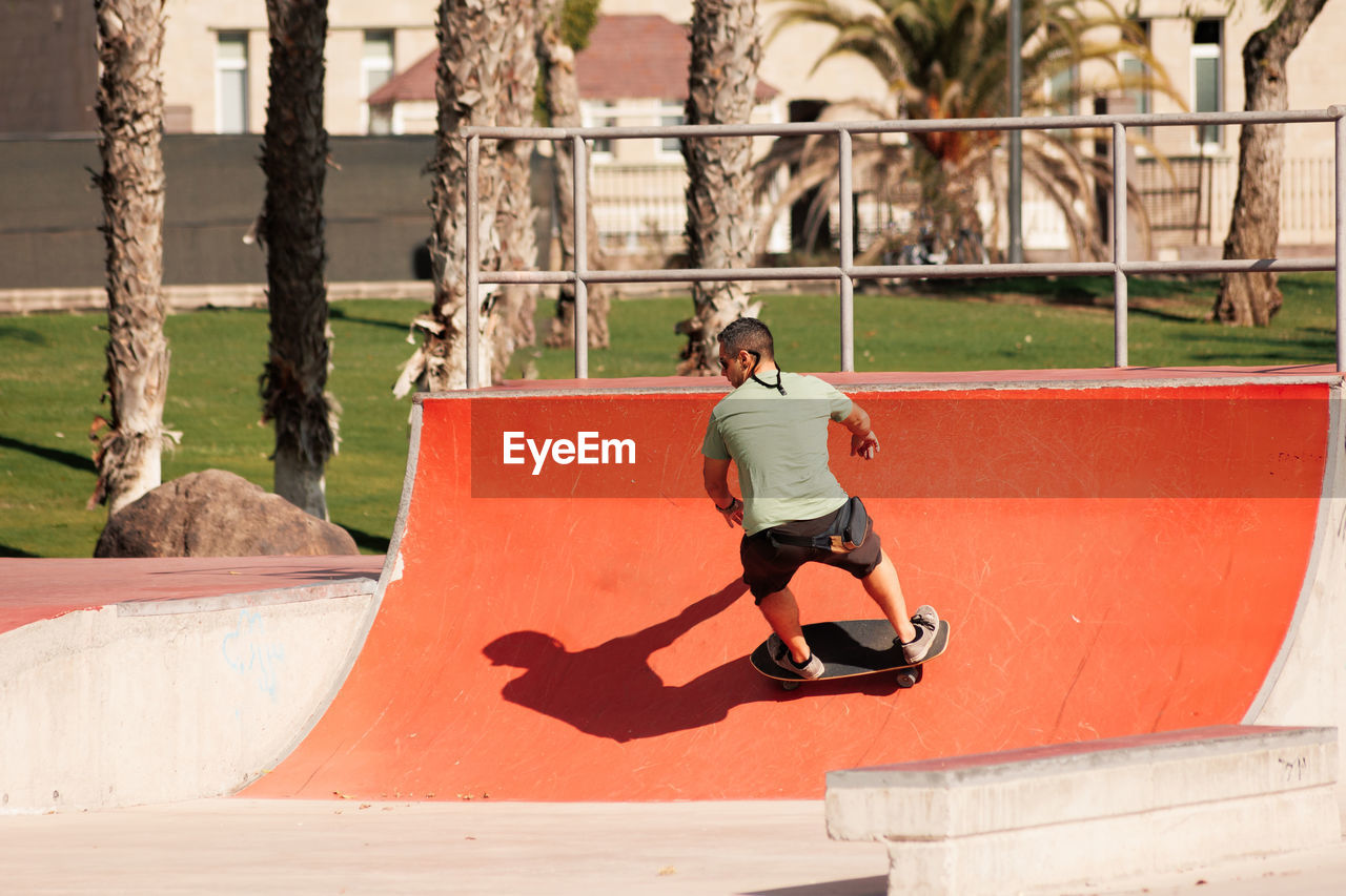 Man riding skateboard in urban street skatepark. casual guy wearing shorts and t-shirt.