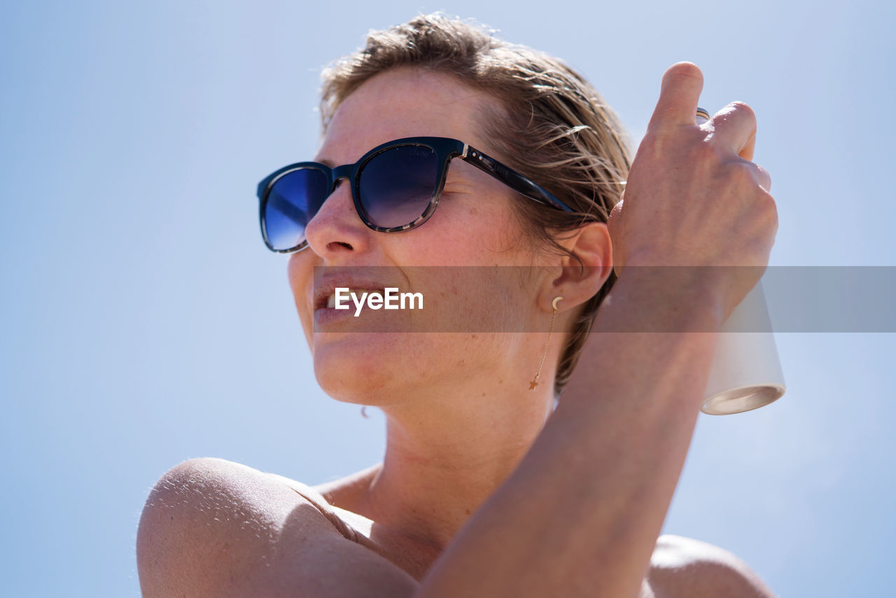 Low angle view woman with short hair enjoying sunshine wearing sunglasses