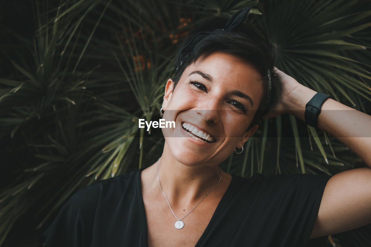 Portrait of smiling woman by plant