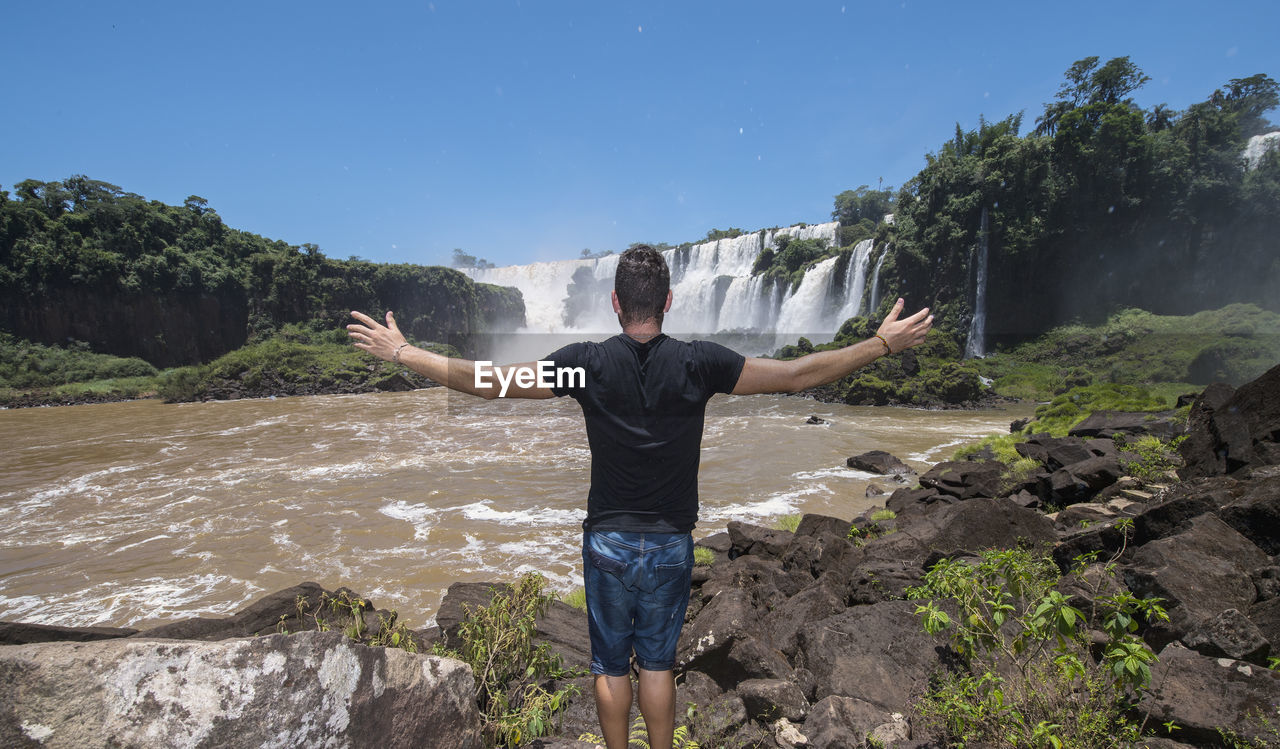 Young man posing in front of the iguacu waterfalls in argentina