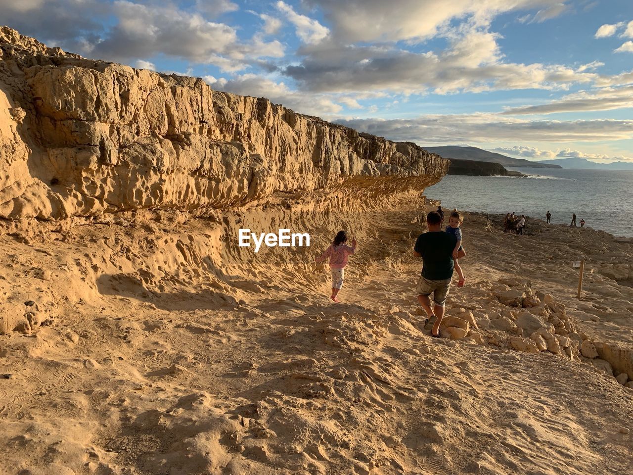 Rear view of people at beach against sky