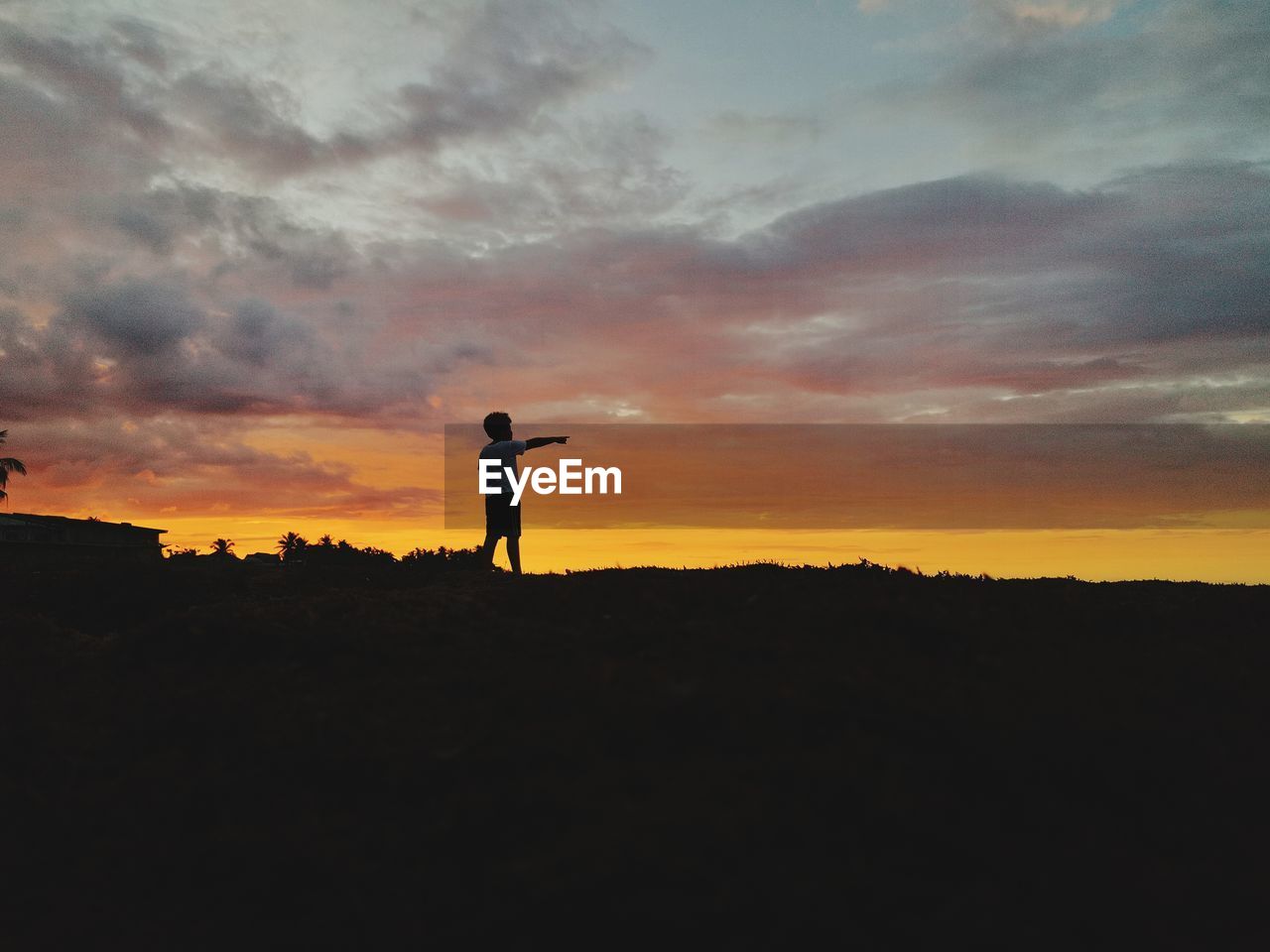 Silhouette man standing on field against sky during sunset