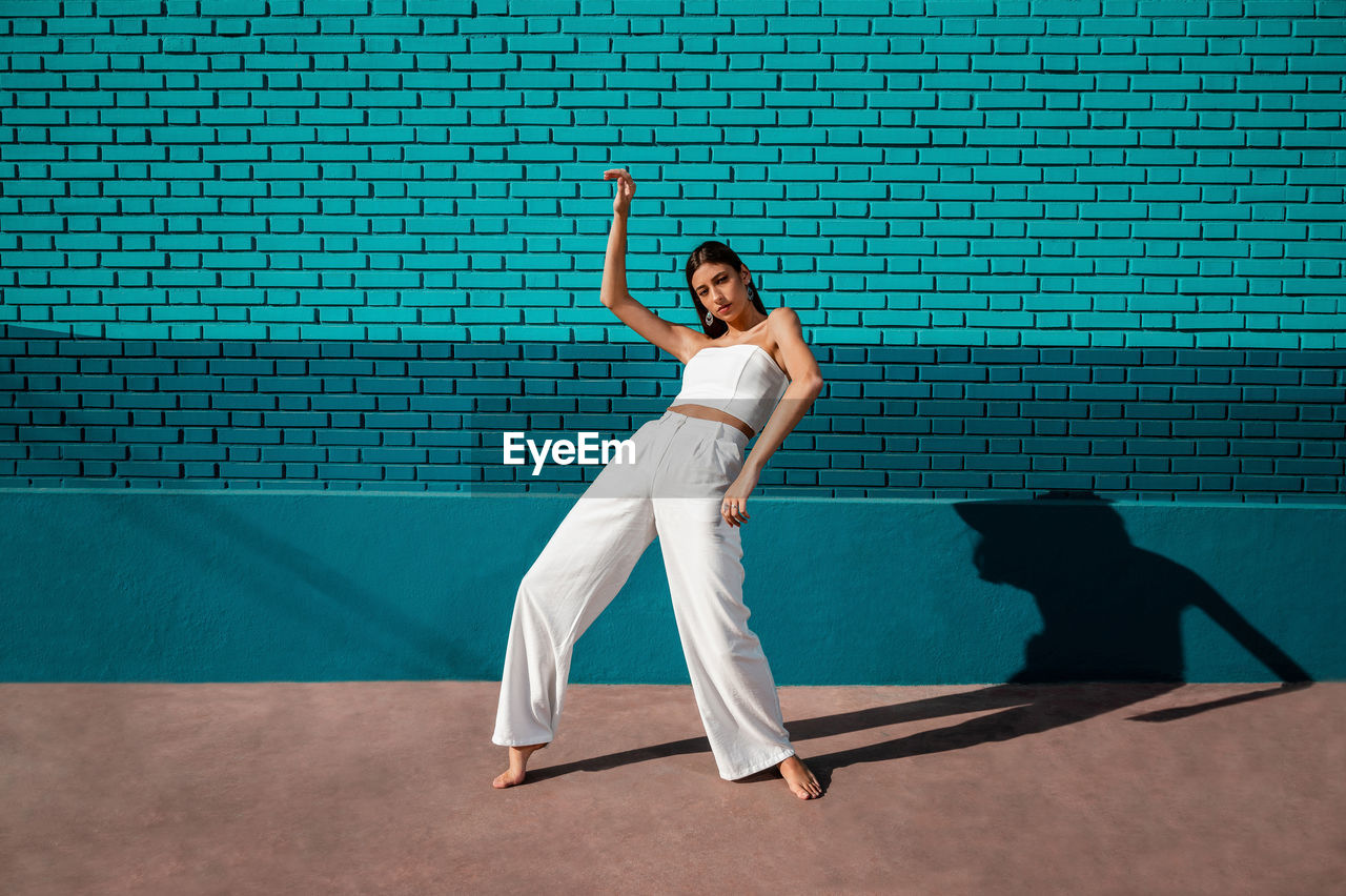 Caucasian woman dancing urban dance with daylight and a green background