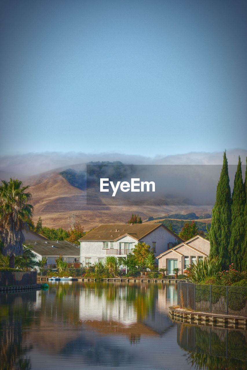 Scenic view of lake by buildings against sky