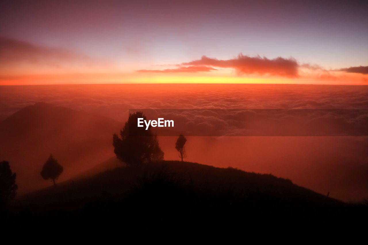 SCENIC VIEW OF SILHOUETTE MOUNTAIN AGAINST ORANGE SKY