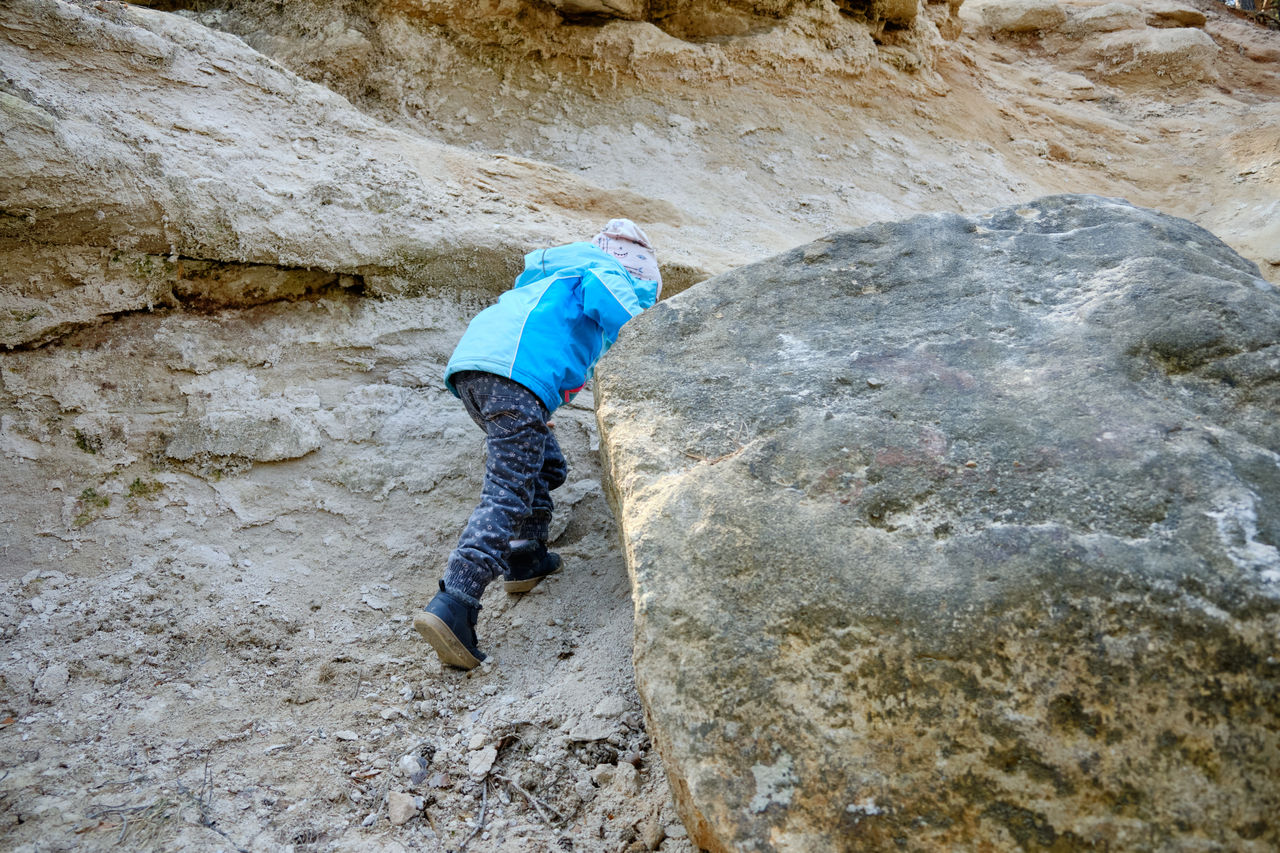 Low angle view of girl climbing on rock