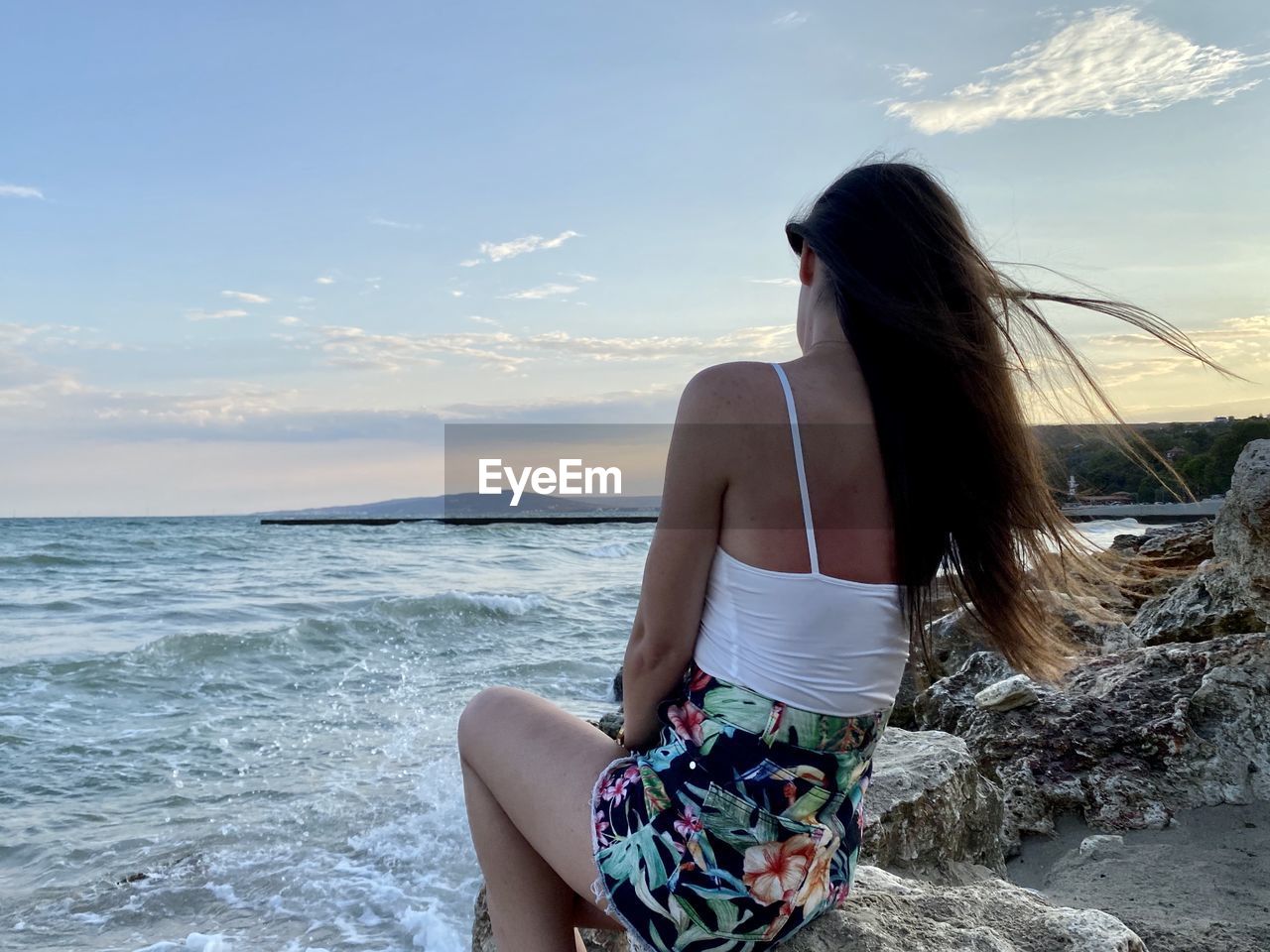 Woman with arms raised in sea against sky