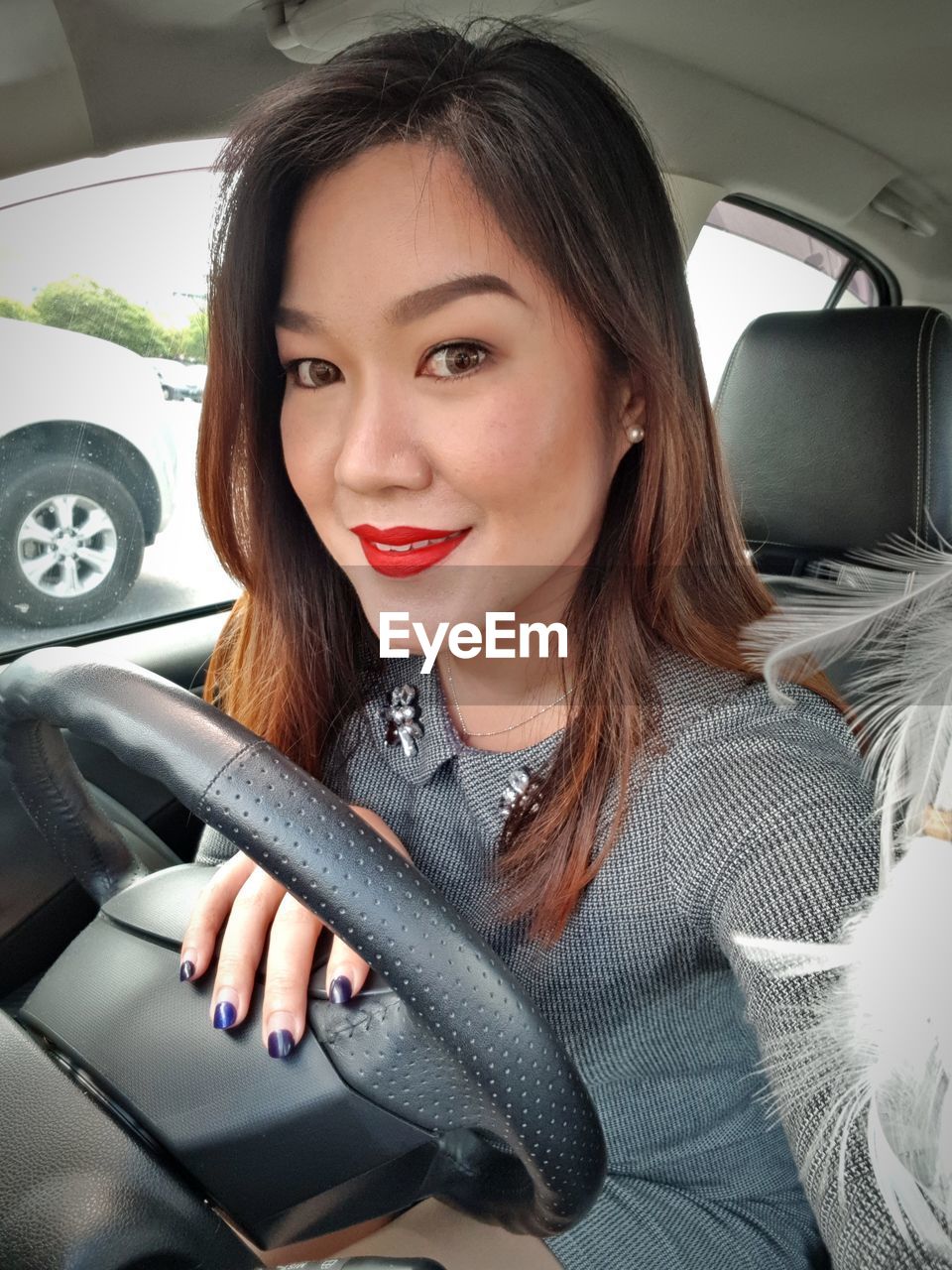 PORTRAIT OF WOMAN SITTING IN CAR WITH CAMERA