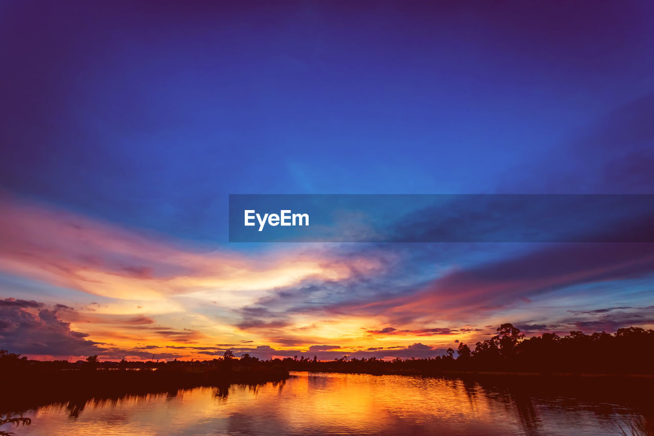 SCENIC VIEW OF LAKE AGAINST SKY DURING SUNSET