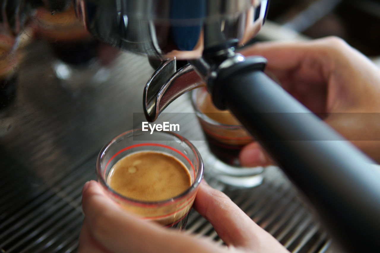 Cropped hand filling coffee in cup at cafe