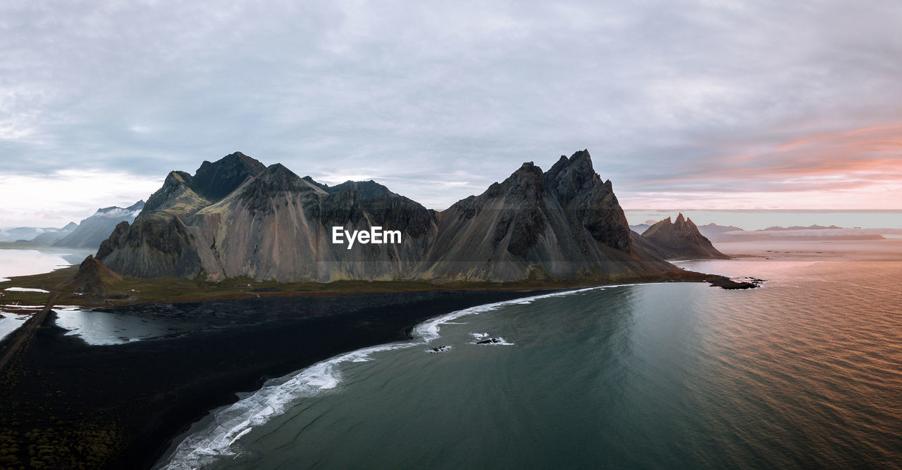 Scenic view of sea mountains against sky during sunset