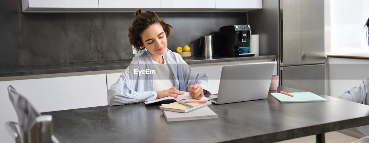 side view of young woman using laptop at table