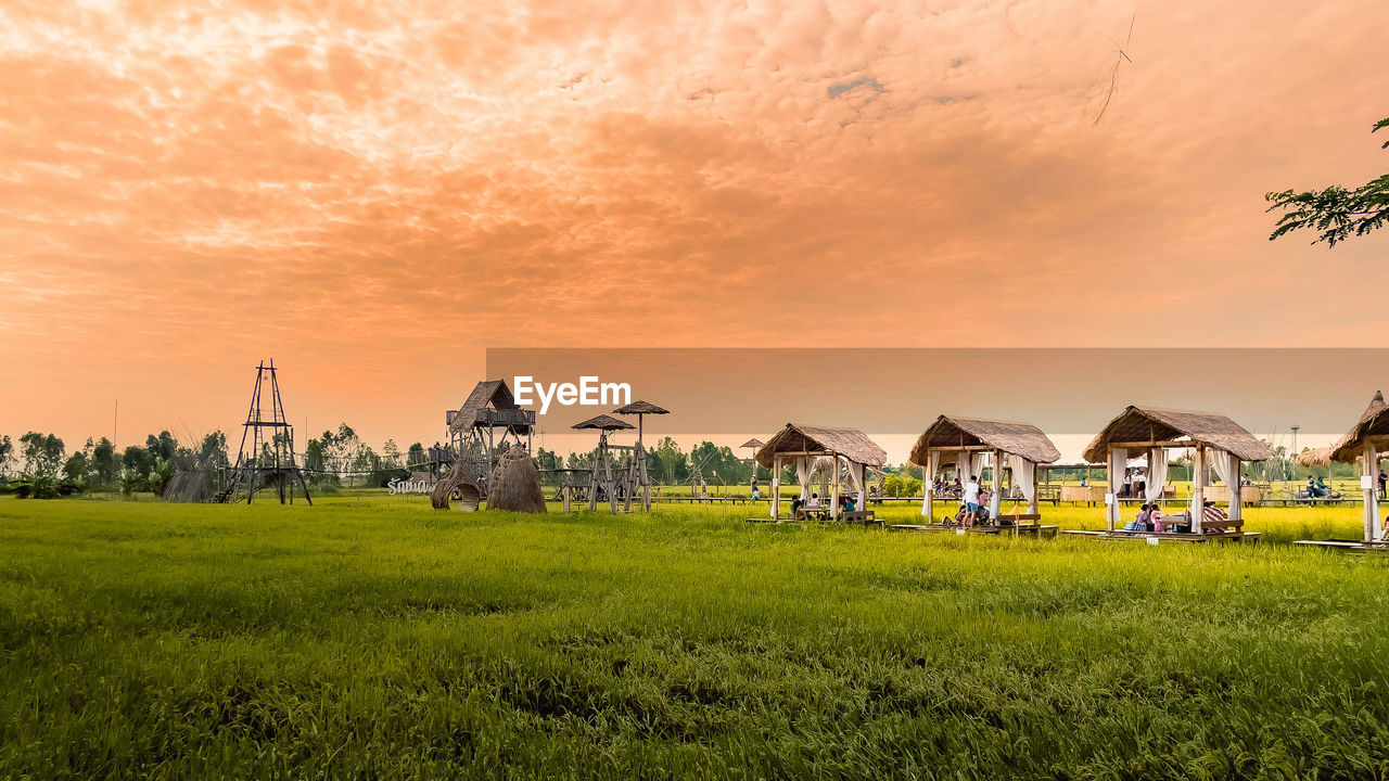 HOUSES ON FIELD BY BUILDINGS AGAINST SKY