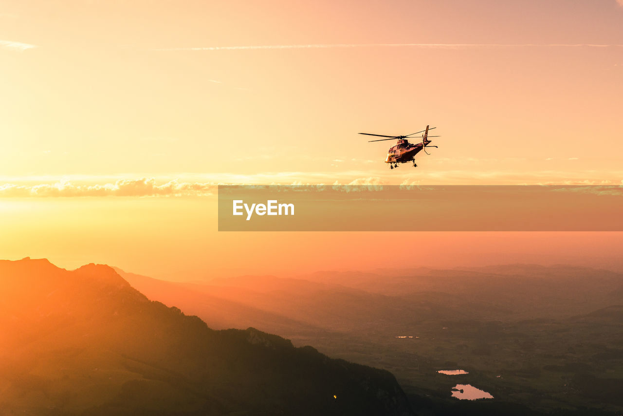 Helicopter flying against sky during sunset