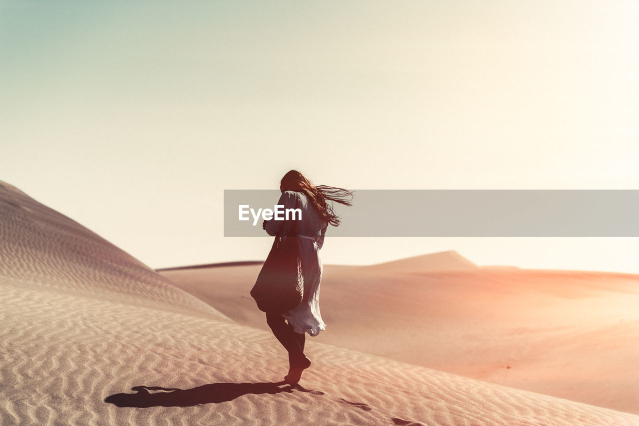 Full length of woman walking on sand at beach against sky