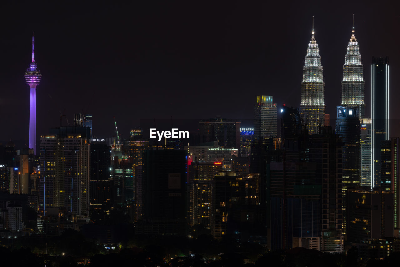 ILLUMINATED MODERN BUILDINGS AGAINST SKY AT NIGHT