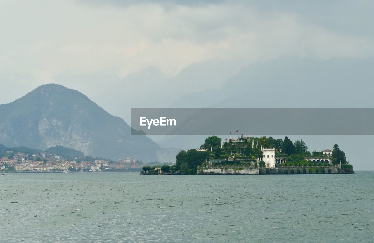 Scenic view of sea by townscape against sky