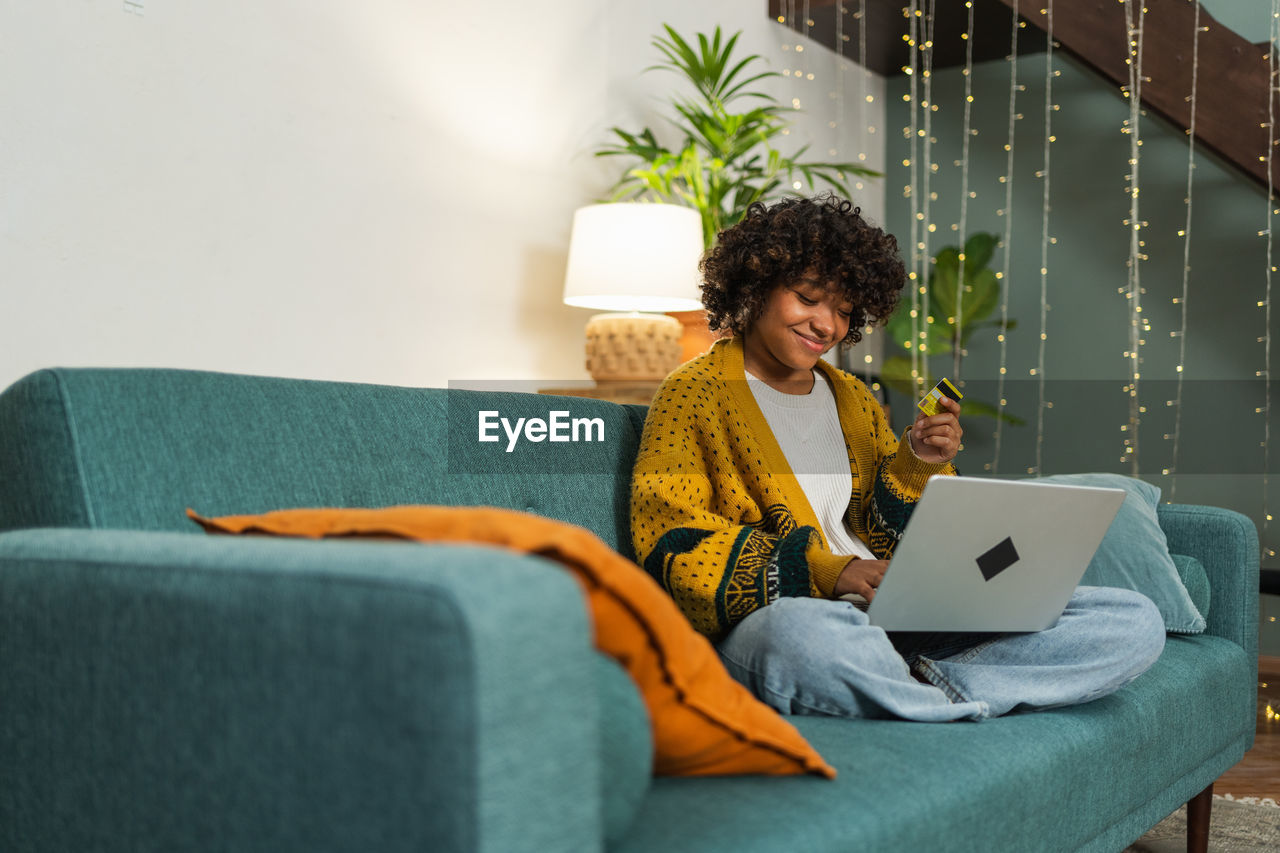 midsection of woman using laptop while sitting on sofa at home