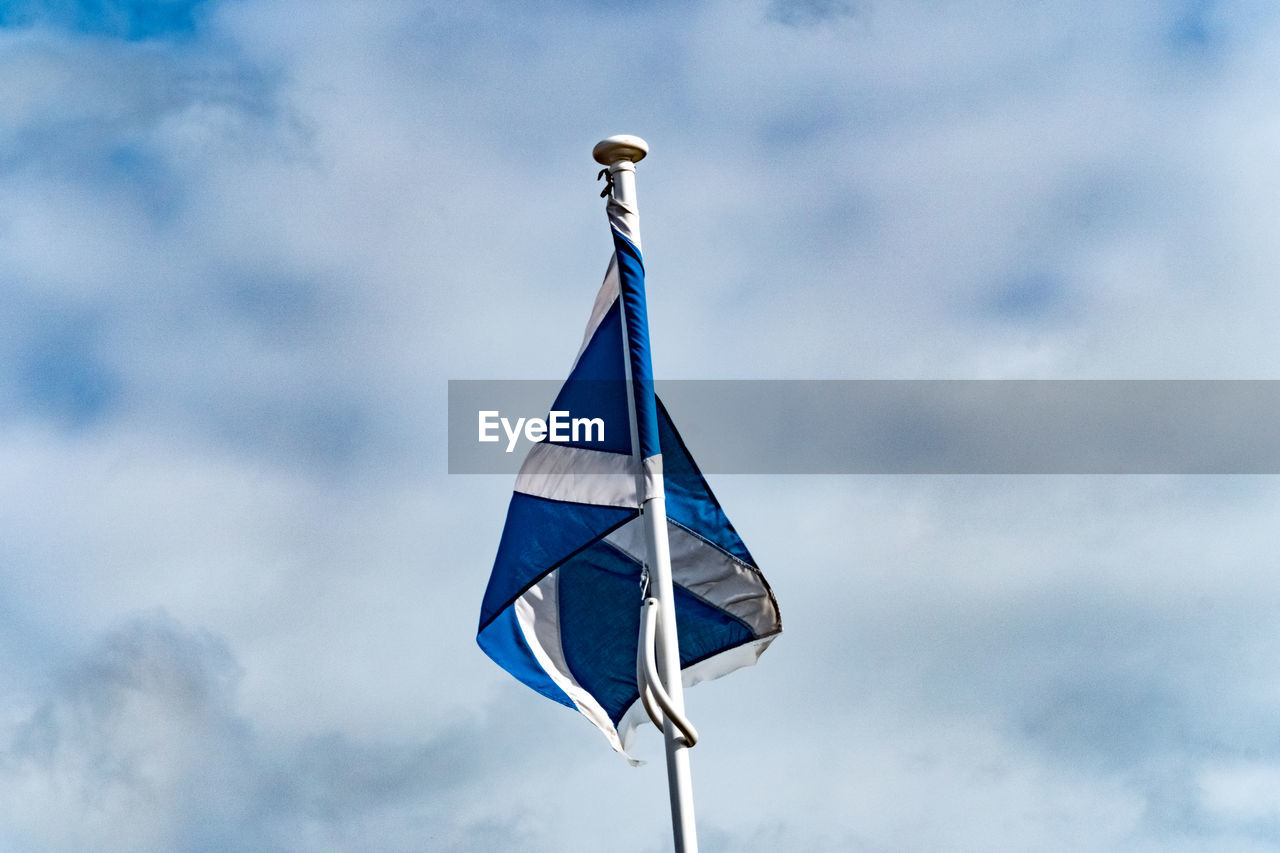 LOW ANGLE VIEW OF FLAGS AGAINST CLOUDY SKY