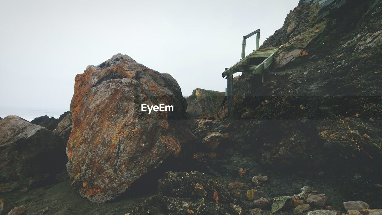 Rock formations at beach against clear sky