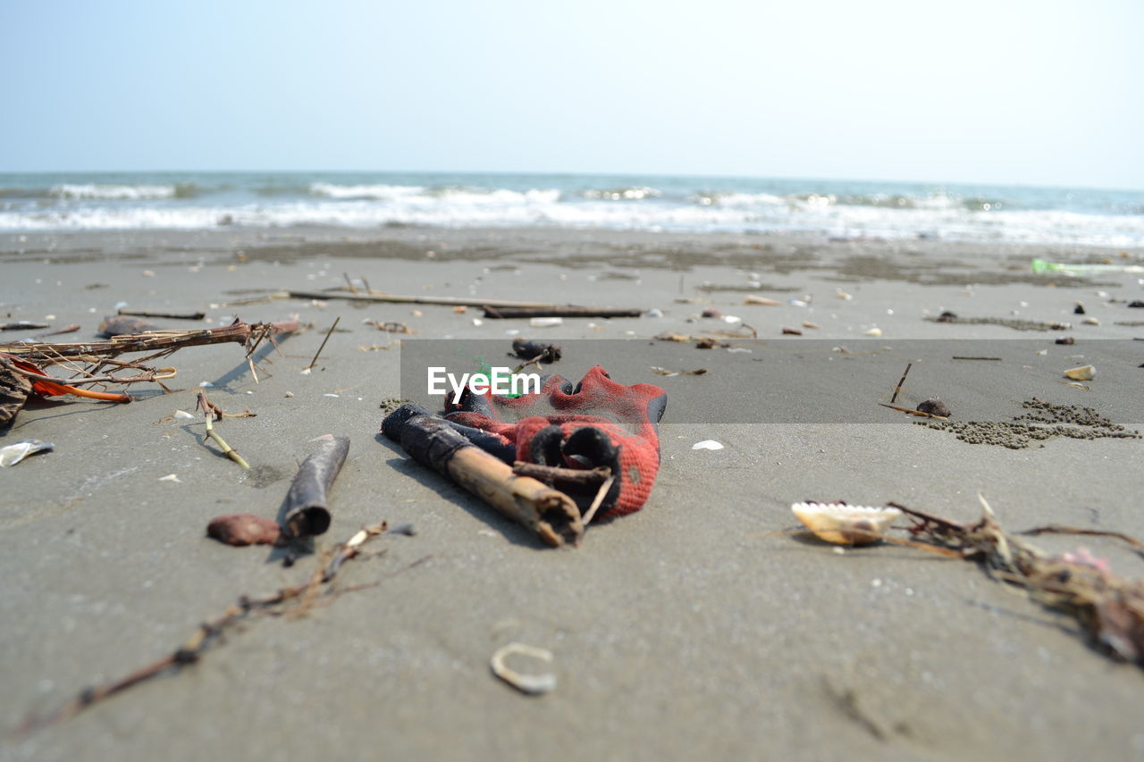 Surface level of sand and garbage at beach against sky