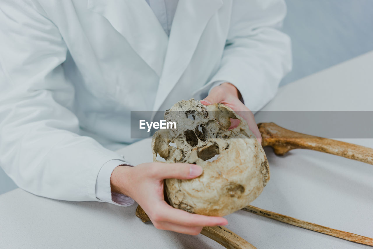 Human skull in handwith bones around and studying medic