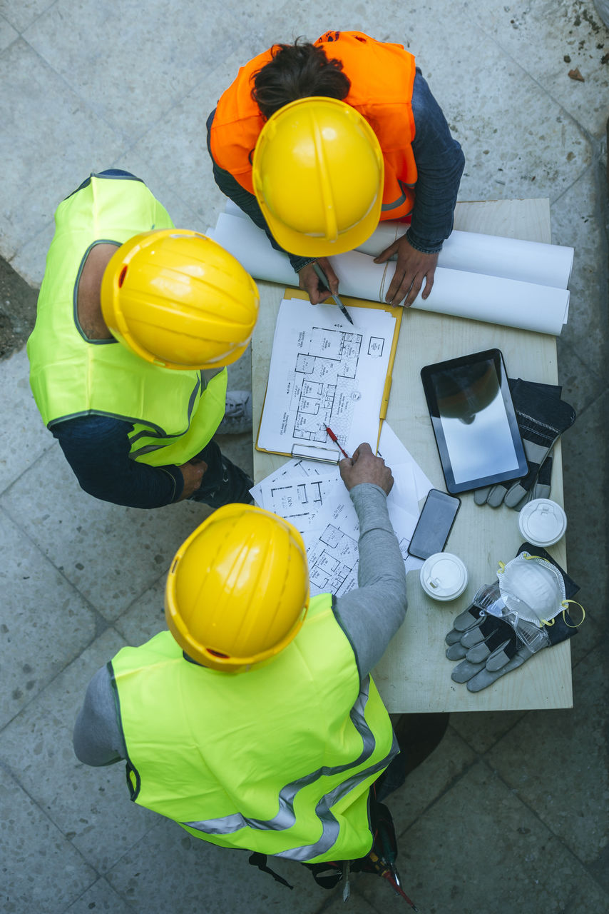 Woman and two men in workwear discussing construction plan