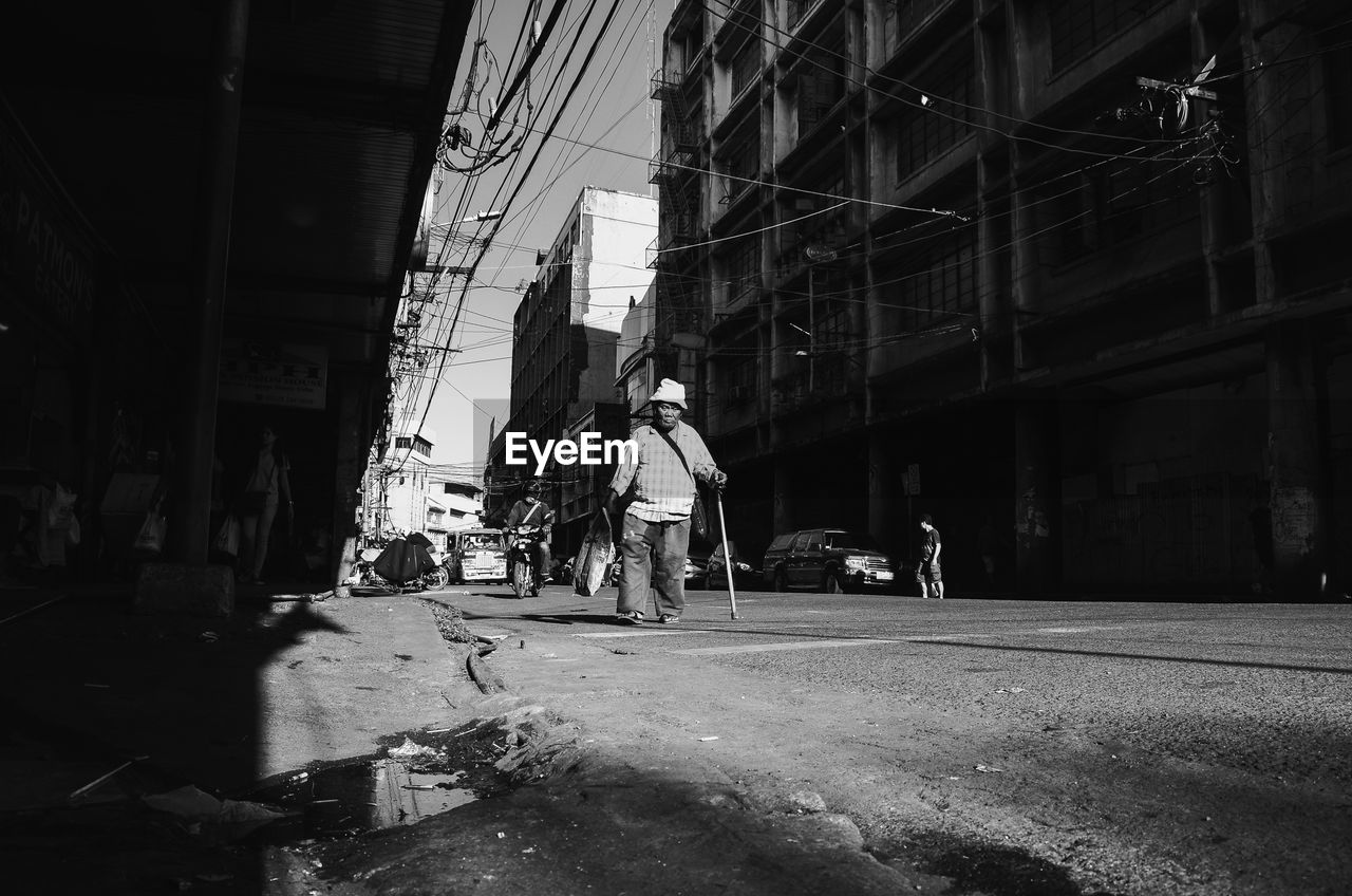 Man walking on road amidst buildings in city