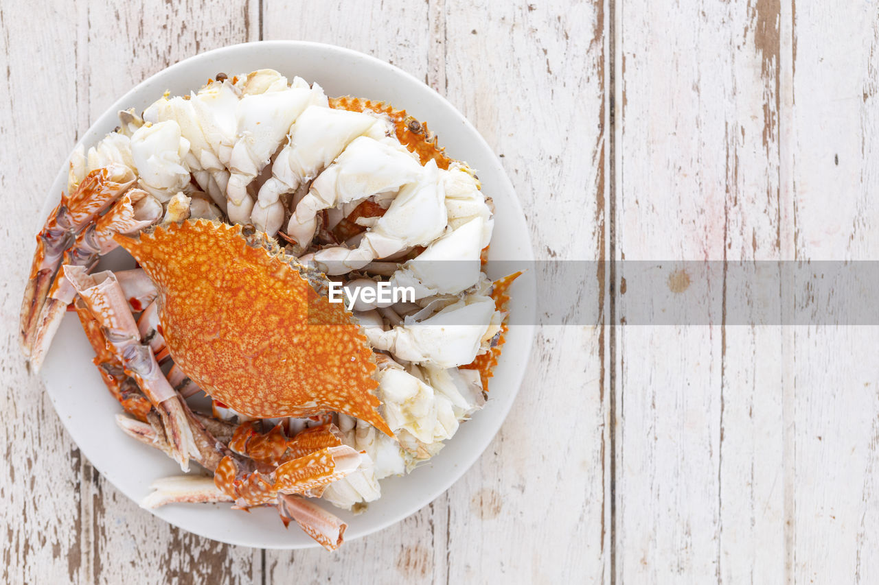 Steamed crabs in white ceramic plate, top view, flat lay, blue swimming crab, flower crab, blue crab