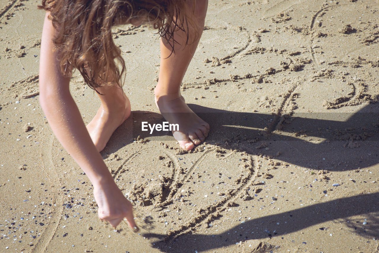 Full length of girl making heart shape on shore at beach