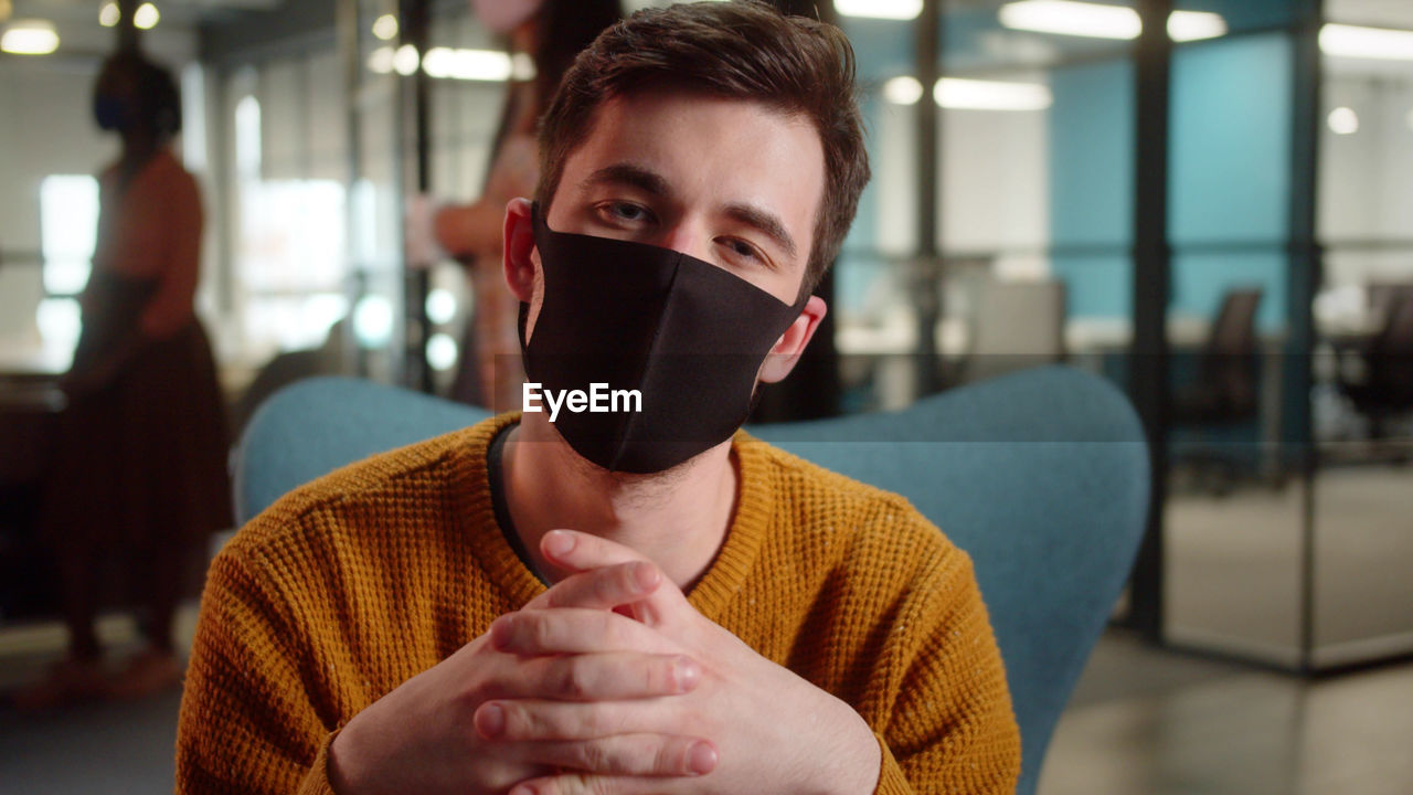 Portrait of smiling man wearing mask in office