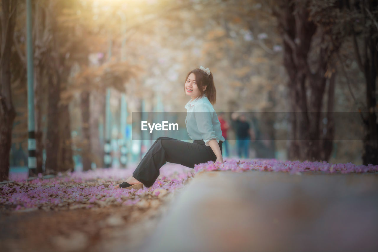 FULL LENGTH OF WOMAN SITTING OUTDOORS