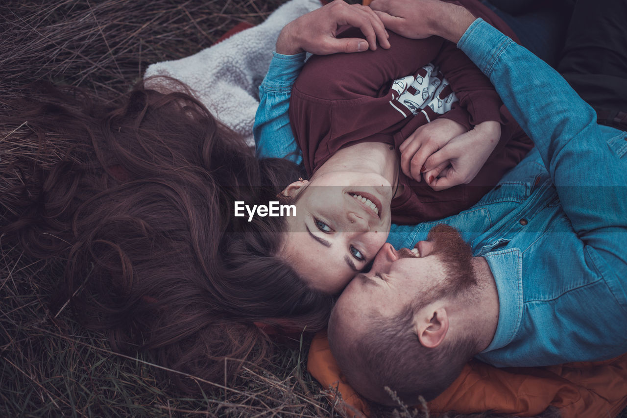 High angle view of couple lying on grass outdoors