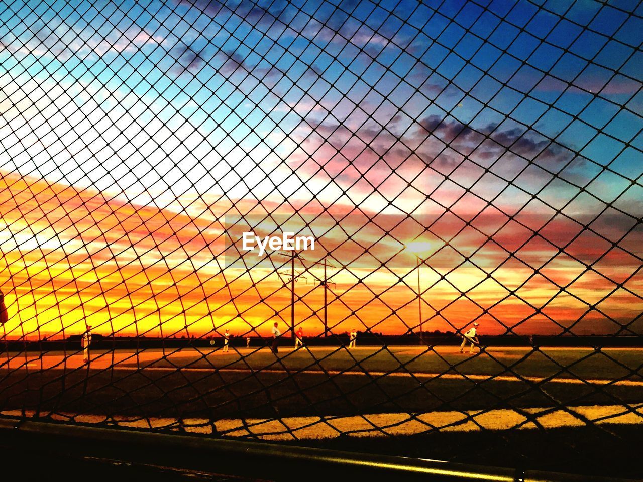 Chainlink fence against sky during sunset