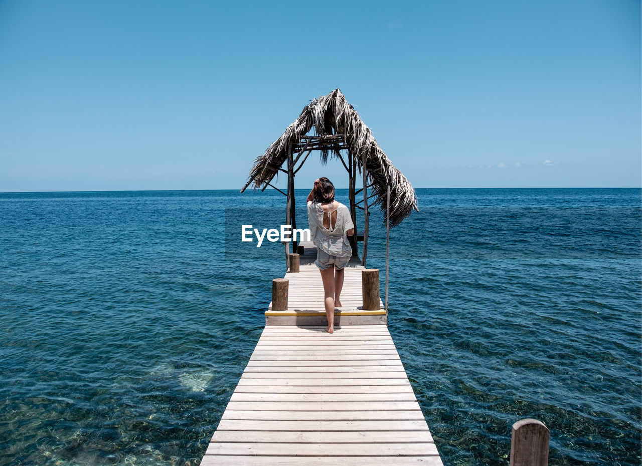 Rear view full length of young woman on pier amidst sea