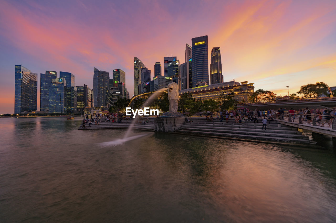 VIEW OF CITY AT WATERFRONT AGAINST SUNSET SKY