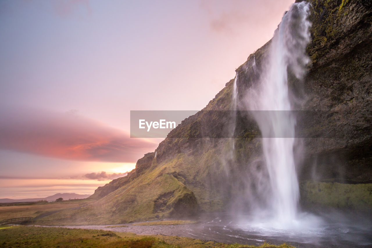 Scenic view of waterfall against sky during sunset